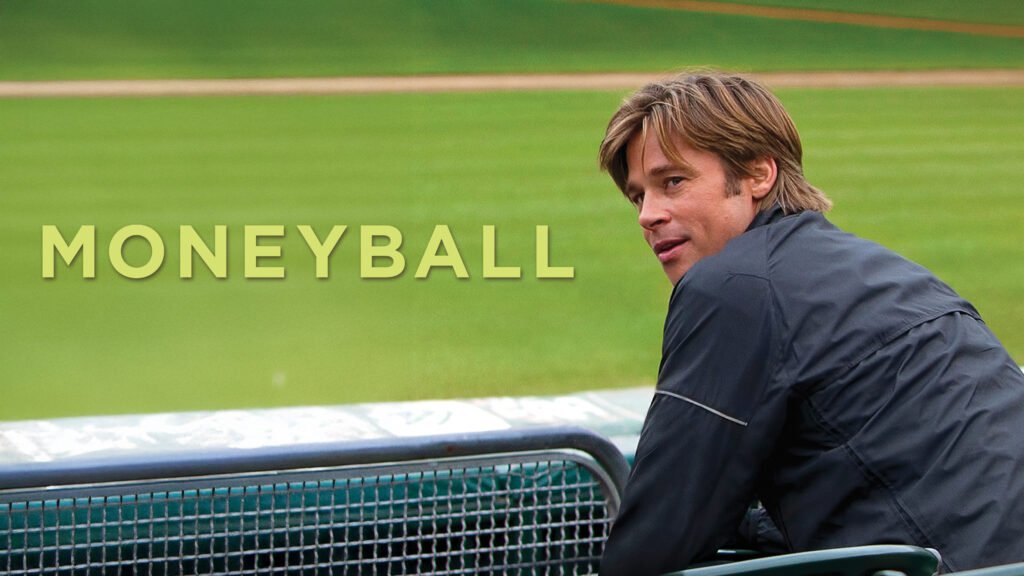 Brad Pitt as Billy Beane leans on a dugout railing, looking out over a green baseball field, with the Moneyball title beside him.